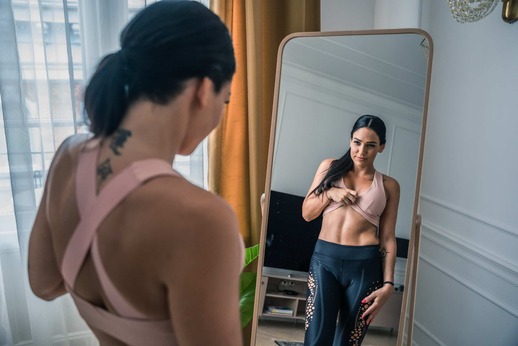 a woman looking to her body in mirror